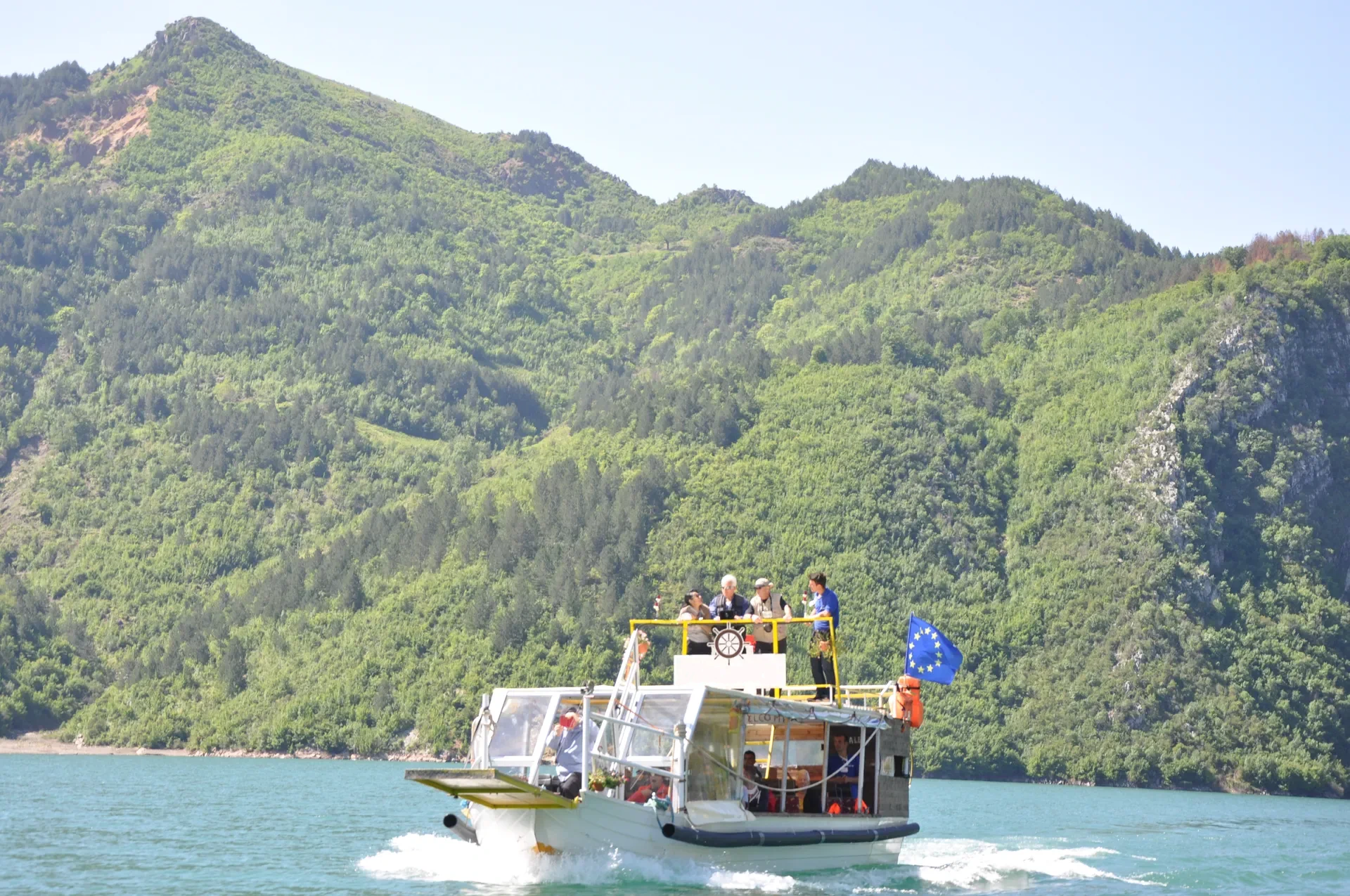 Steep vertical canyon walls rising hundreds of meters above the deep blue reservoir waters.