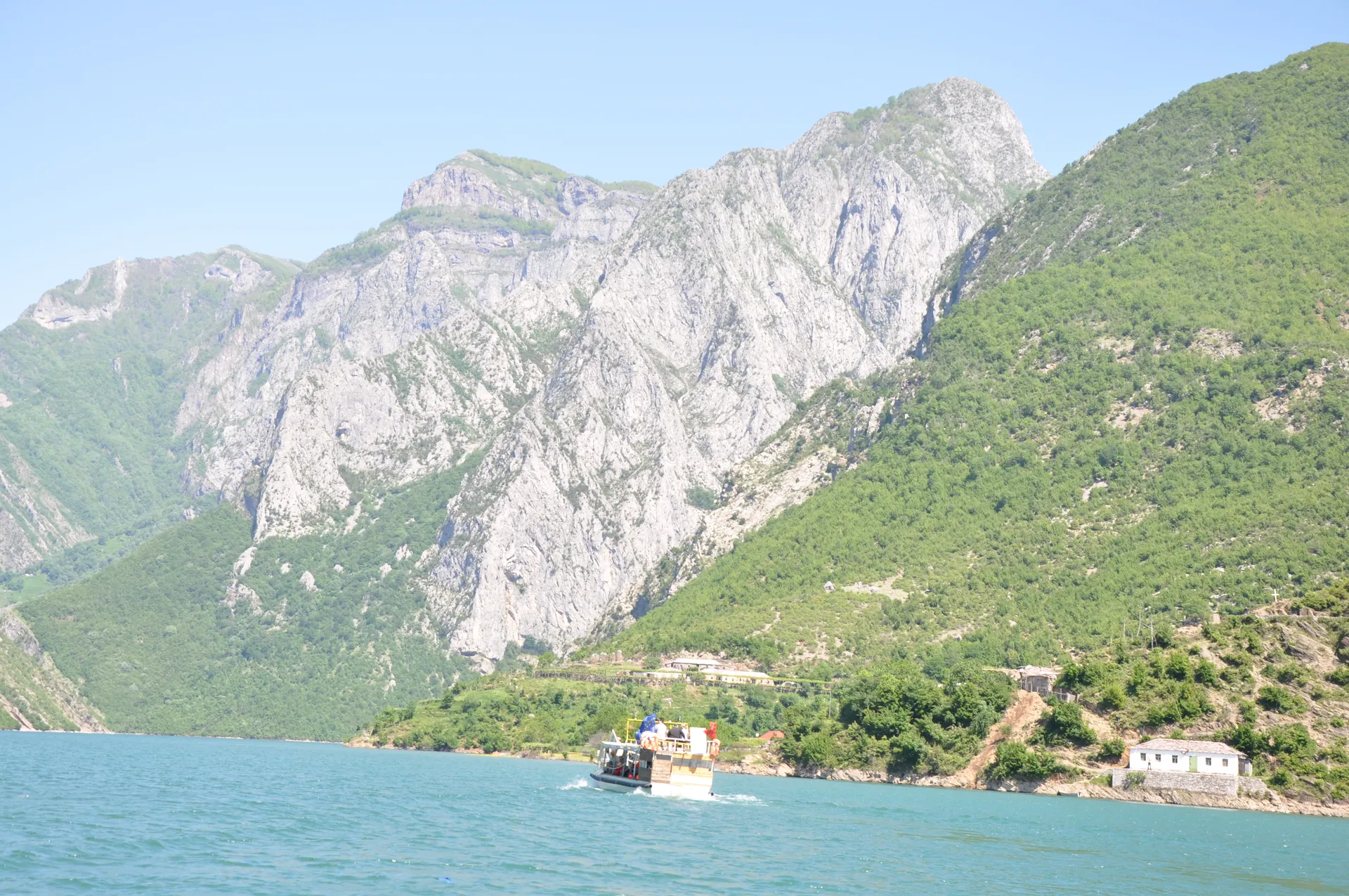 Dramatic limestone peaks of the Accursed Mountains towering above the lake in early summer.