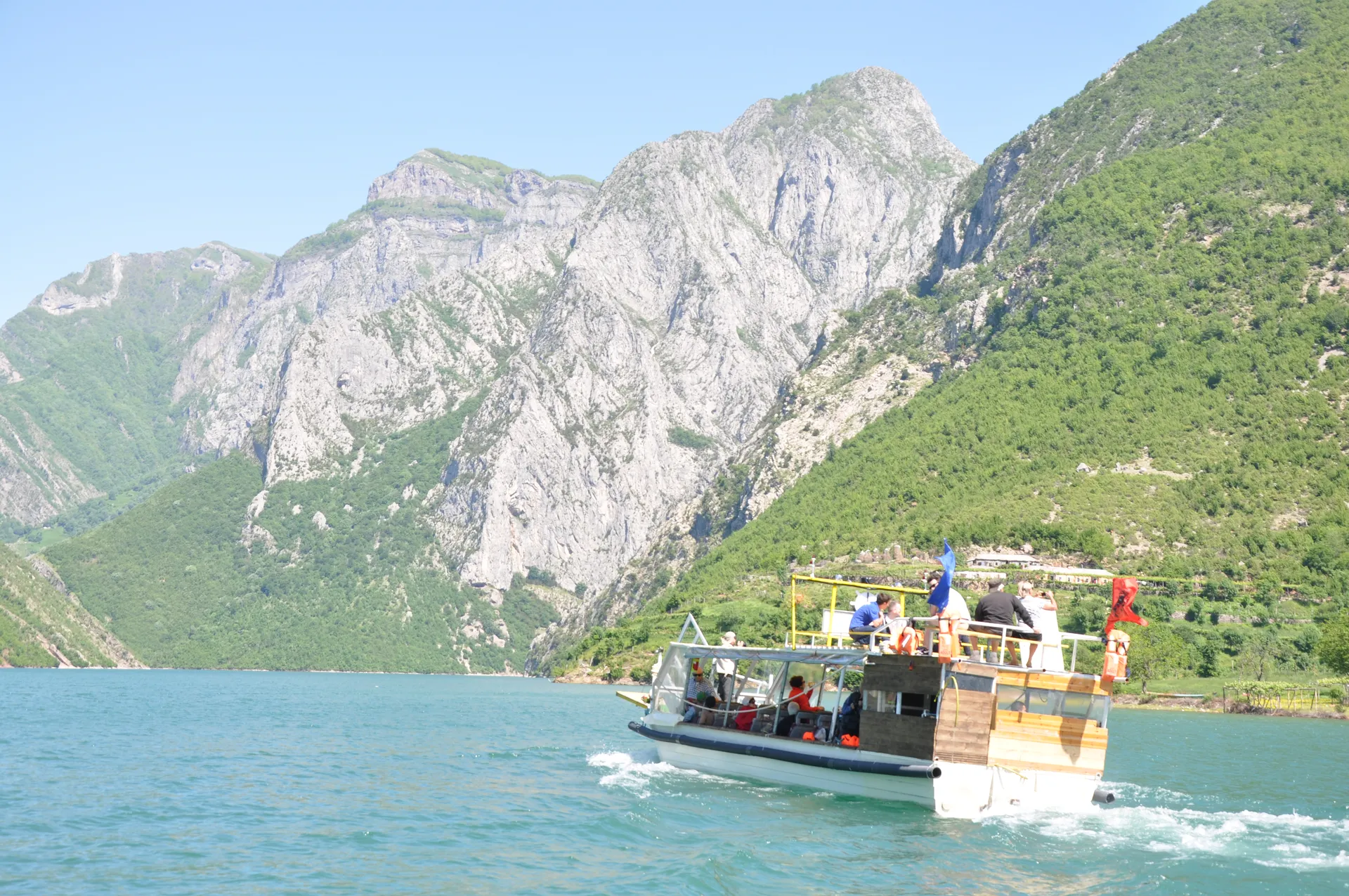 Tour boat navigating past the rugged mountain landscapes of the Koman Lake.