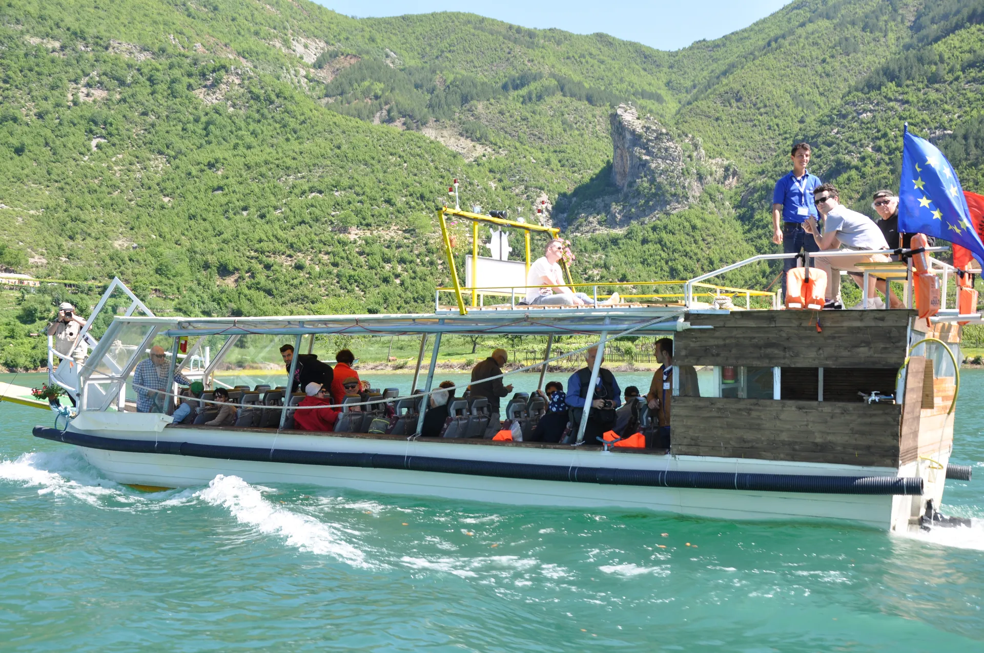 Tour boat carrying passengers through the bright turquoise canyon waters.