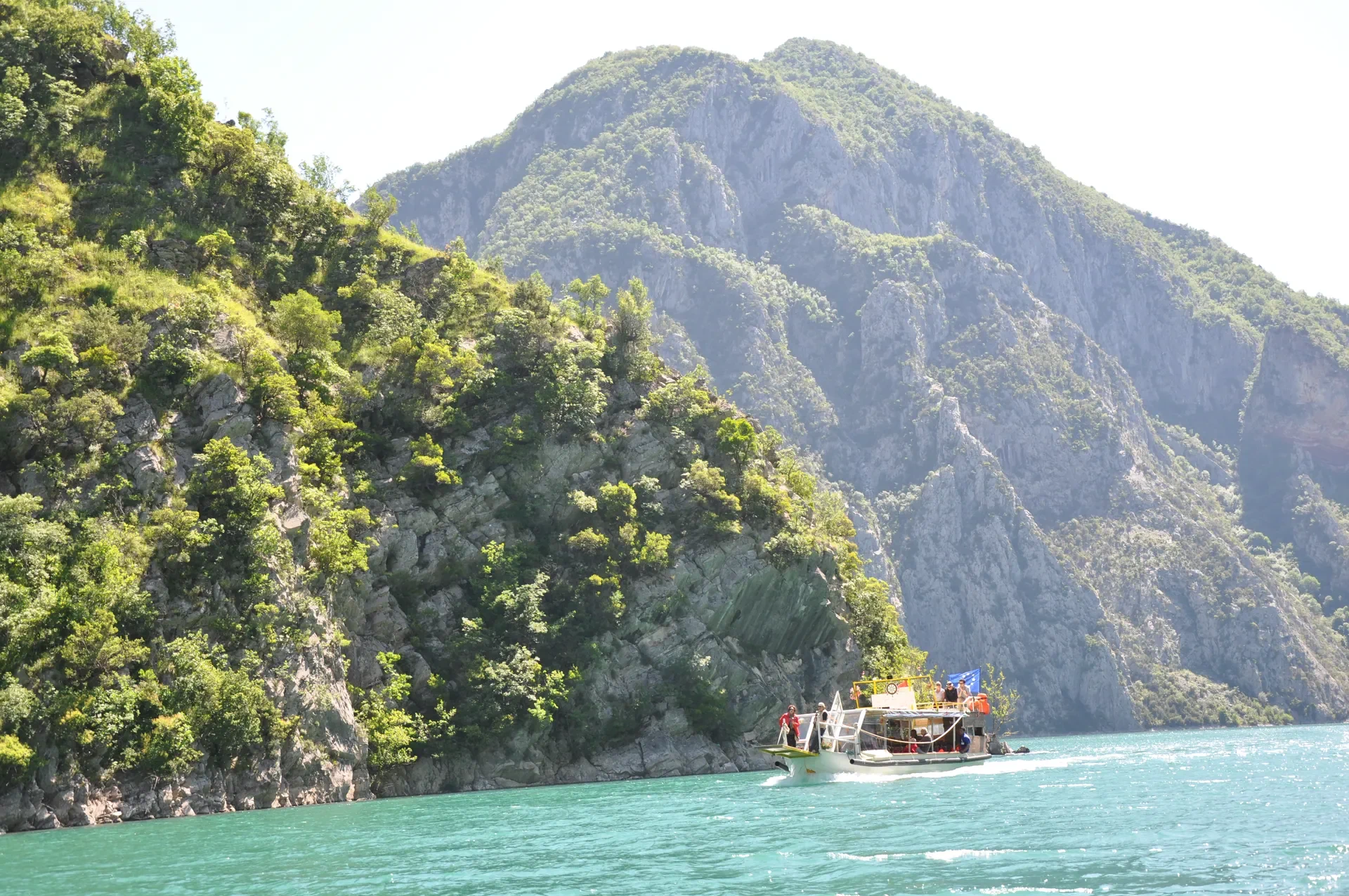 A tour boat making its way through the towering mountain landscape.
