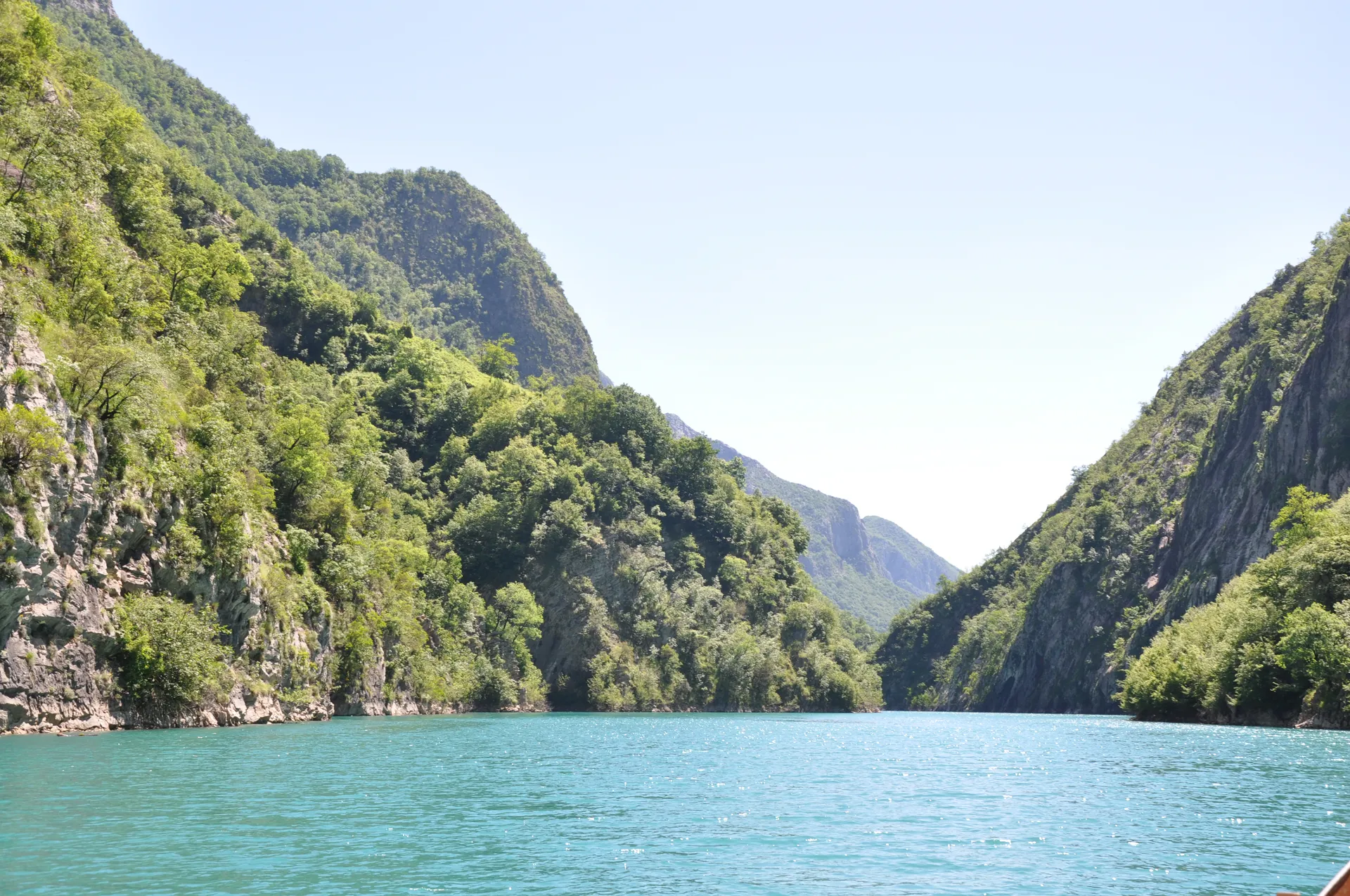 Tranquil turquoise waters of the Shala River flanked by sunlit green canyon walls.