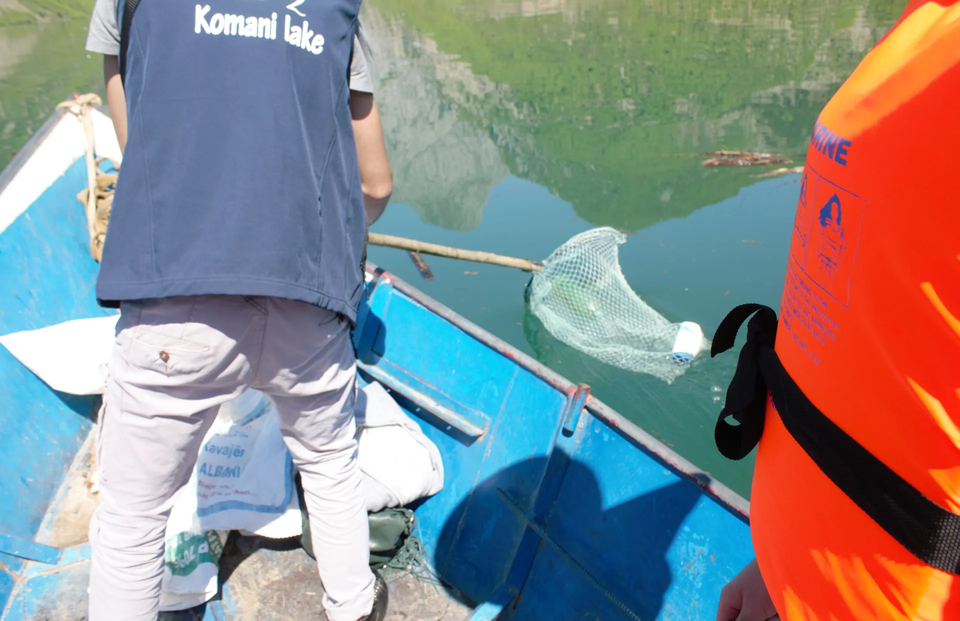 Tour guide using a net to gather some debris from the lake.