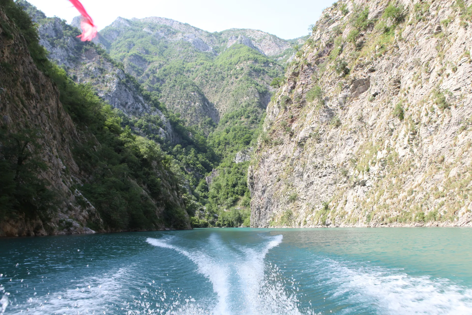 The white wake of the boat cutting through the deep canyon waters.